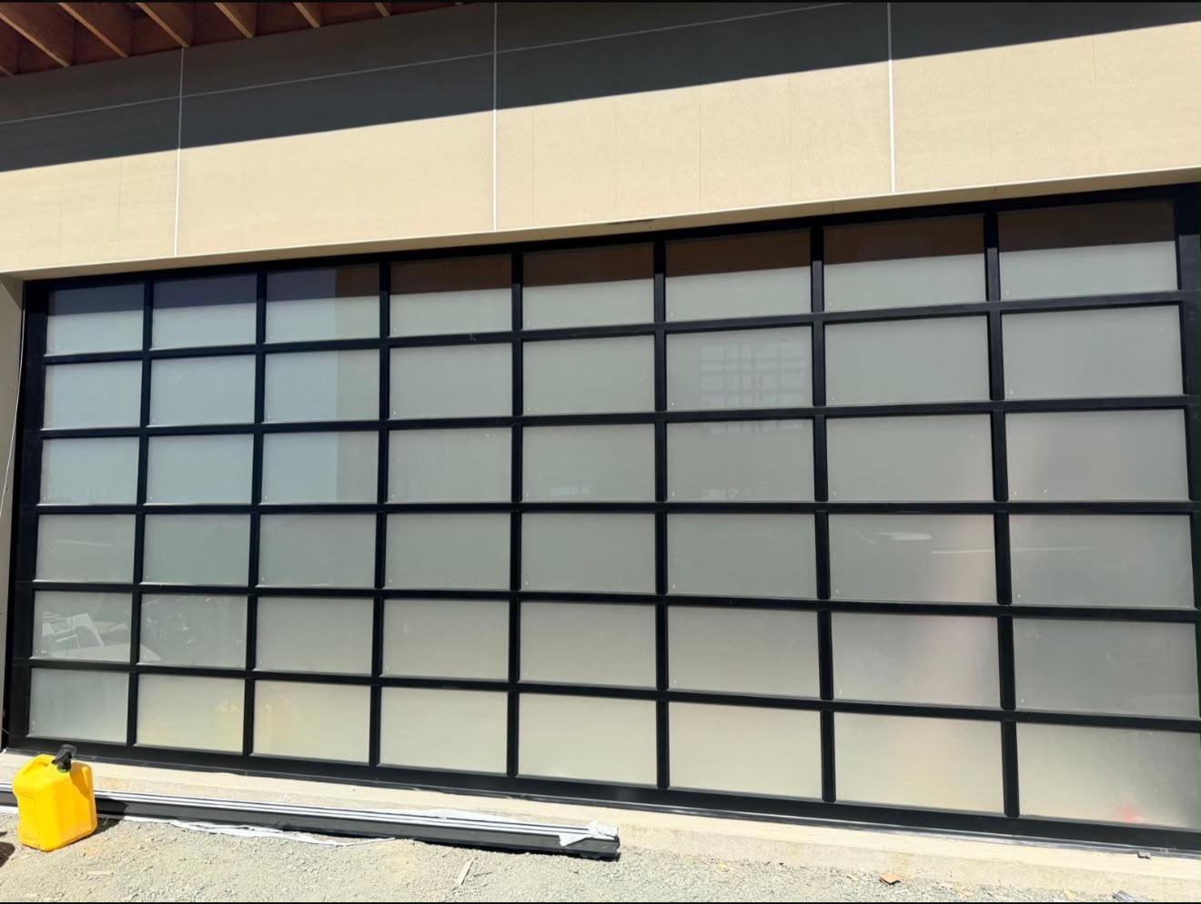Black aluminum frosted-glass coastal garage door on a Santa Cruz Westside home